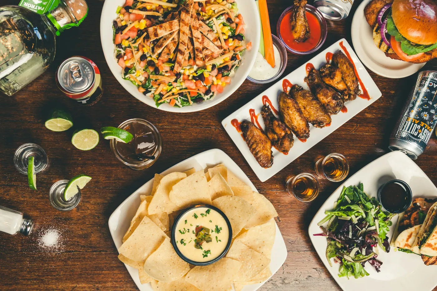 An overhead spread of shared plates and drinks on a wooden table