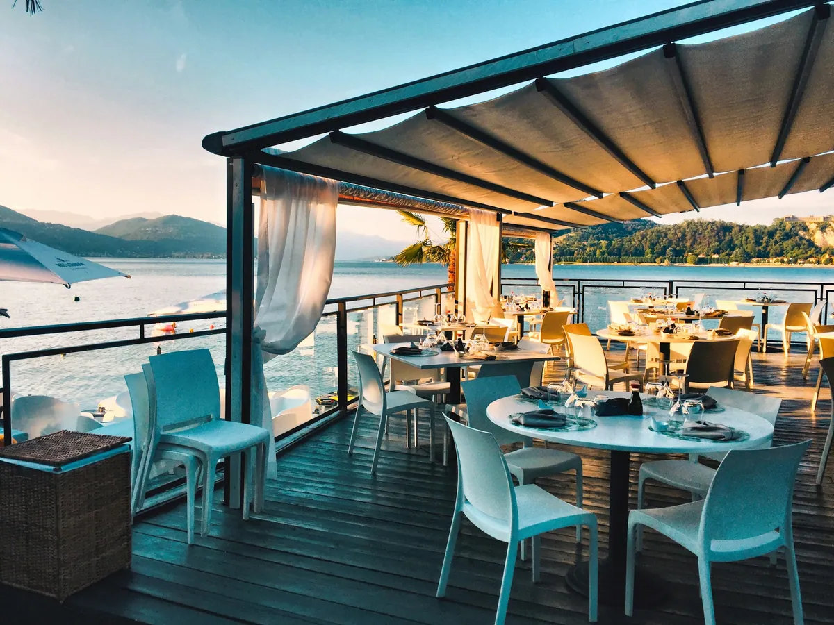 A waterfront restaurant terrace set for dinner at golden hour